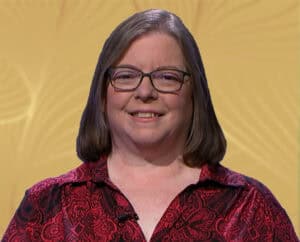 Woman smiling at the camera in a red patterned blouse.